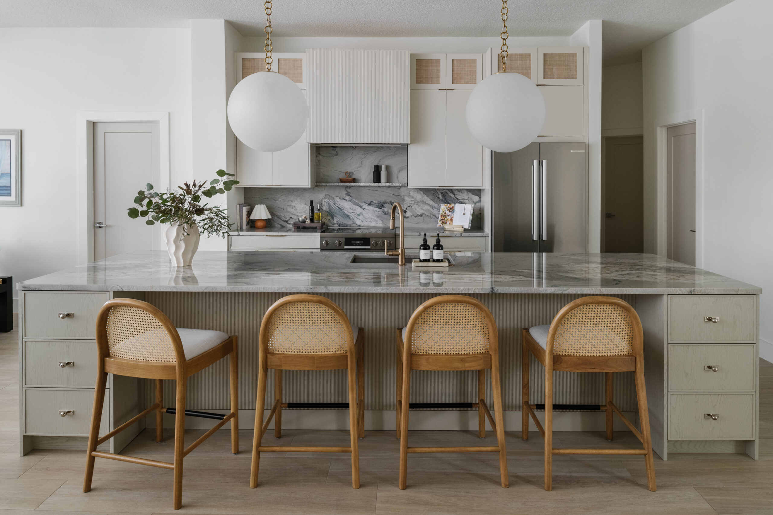 Neutral contemporary kitchen with oversized globe pendants and quartzite countertops