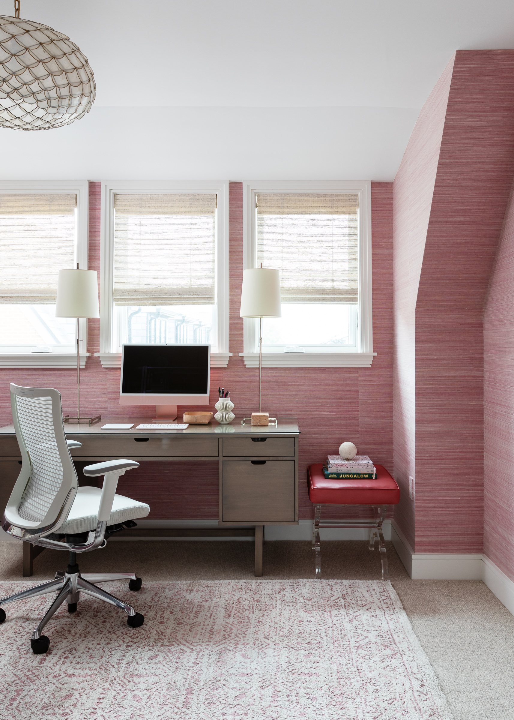 Home office treehouse feel woven roman shades grasscloth bermuda wallpaper fuschia magenta walls boho rug mid-century desk capiz semi-flush mount light fixture